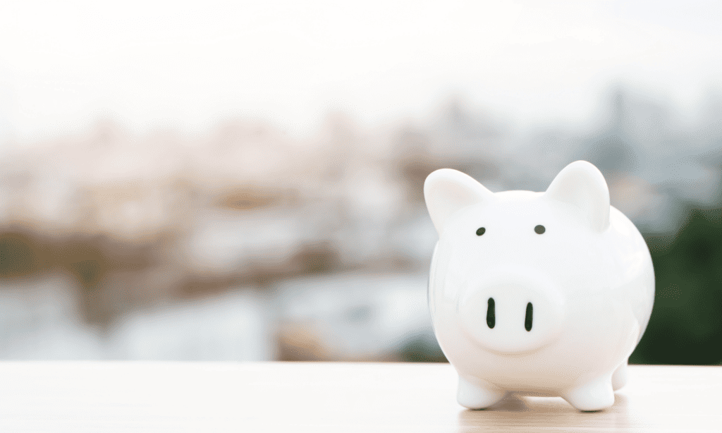 Pension planning: image of a white piggy bank on a table with a blurred background.