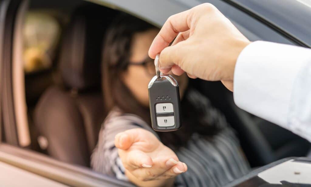 Getting tax on employment benefits right: image shows a lady sitting in a company car. In the foreground someone is handing her the keys.