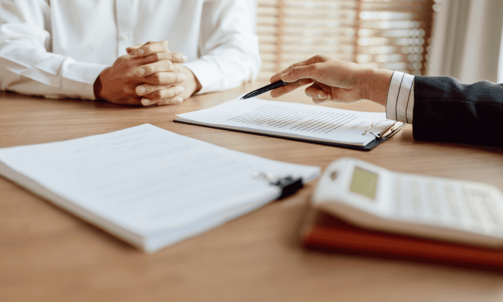 employer update 2025- image of documents and a calculator on a table and two people in suits are signing them